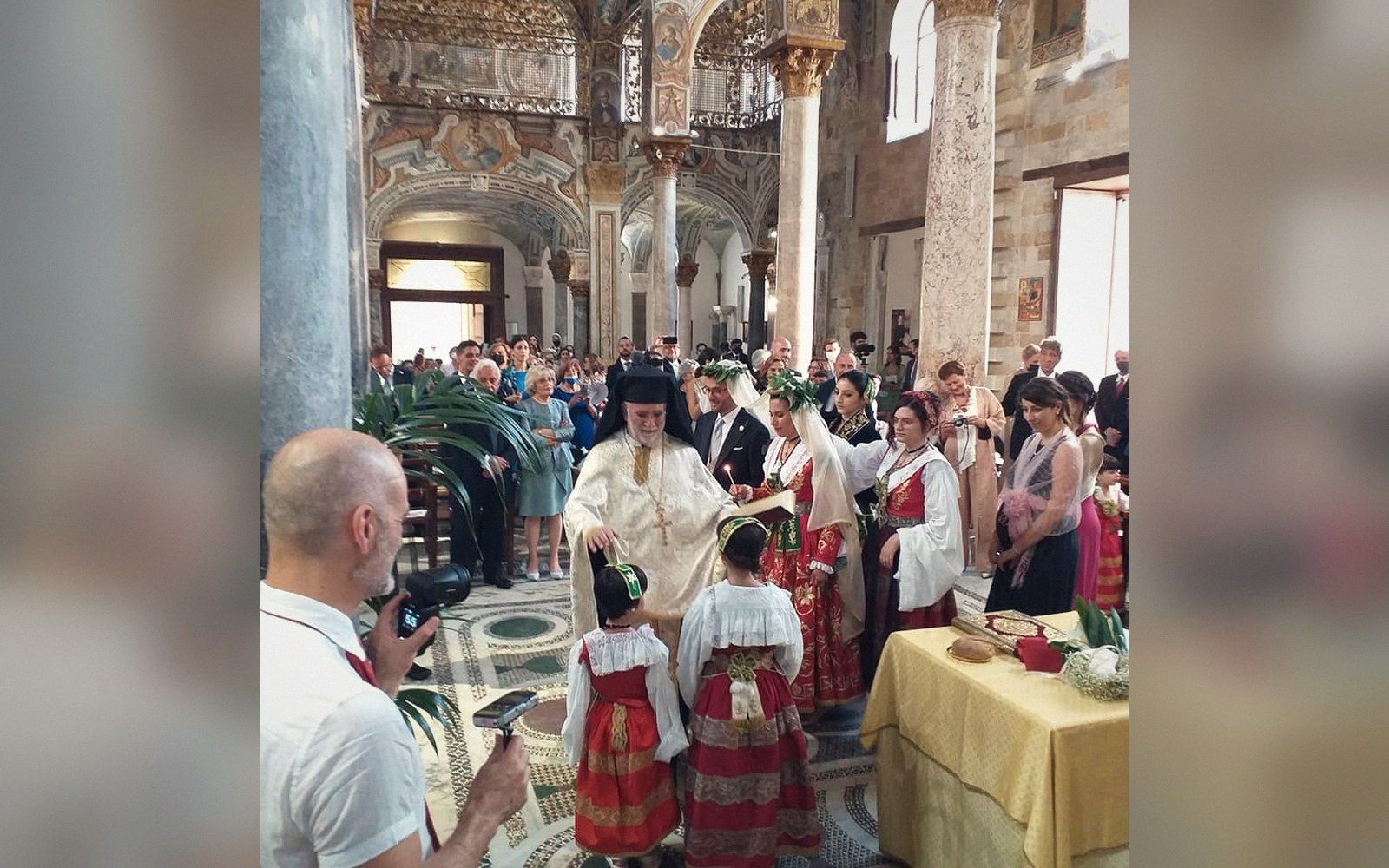 A Byzantine-rite wedding party in embroidered dress inside a mosaic-lined church