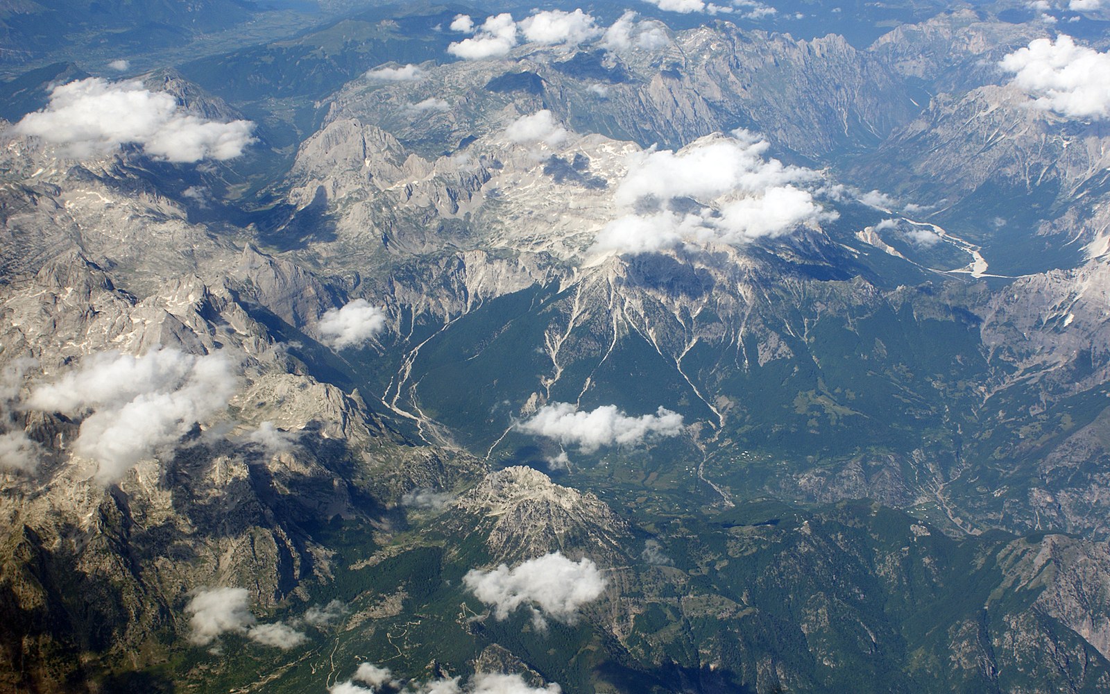 Mountain ranges and river valleys under scattered cloud, seen from the air